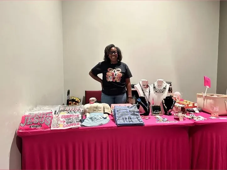 A vendor table with a pink cloth, T-shirts and jewelry