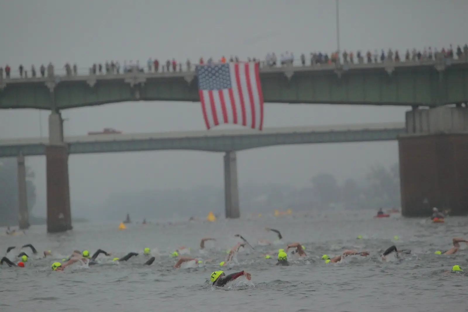 Swimmers in the Savannah River during the swim leg of Ironman 70.3 Augusta, with spectators on the bridge above.